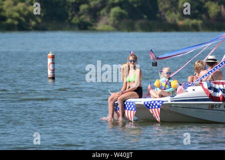 People celebrating on real party boats on July 4 in California clear lake holiday boat parade family families sunny day of fishing and tanning in heat Stock Photo