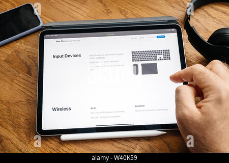 Paris, France - Jun 6, 2019: Man reading on Apple iPad Pro tablet about latest announcement of at Developers Conference WWDC - showing the Mac Pro workstation with acceosries and wireless wi-fi Stock Photo