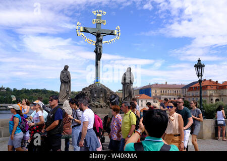 Tourists in front of Statue of the Crucifixion on the Charles Bridge in Prague, Czech Republic Stock Photo