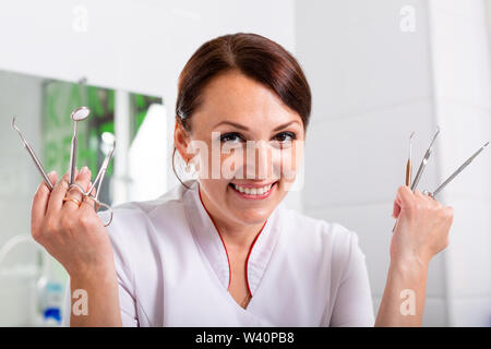 Dentist doctor poses for the camera on the background of the dental office with the patient. Concept healthy teeth, beauty, health. Stock Photo