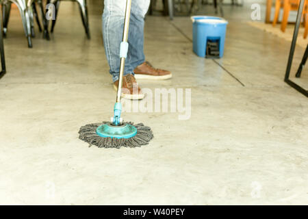 Man worker with mop and bucket cleaning floor in the cafe. Stock Photo