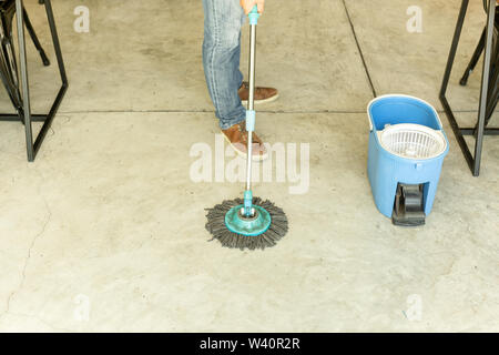 Man worker with mop and bucket cleaning floor in the cafe. Stock Photo