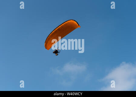 Paraglider flying over sea.Paraglider flies orange paraglider in the blue sky. Paragliding. Stock Photo