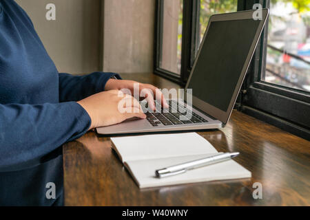 Woman hands using laptop next to notebook Stock Photo
