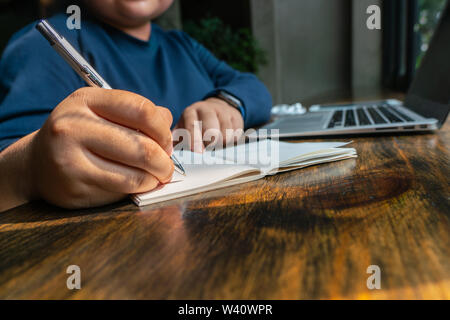 Woman hand holding hand and writing notebook while working Stock Photo