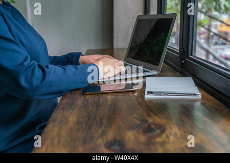 Close up photo of woman hand typing laptop at rustic table  Stock Photo
