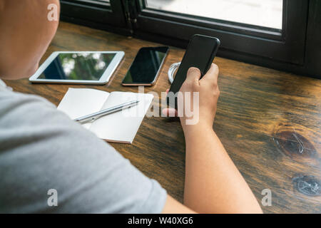 Rear view of businessman using cellphone on rustic wooden table Stock Photo