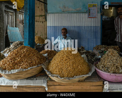 25 Jun 2019shopkeeper in front of Baskets lined up with different kinds of dried fish shop at Neral market District Raigadh Maharashtra INDIA Stock Photo