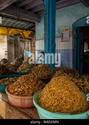 25 Jun 2019shopkeeper in front of Baskets lined up with different kinds of dried fish shop at Neral market District Raigadh Maharashtra INDIA Stock Photo