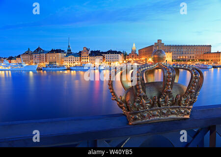 Scenic view of Stockholm's Old Town (Gamla Stan) skyline illuminated at dusk with the royal crown on the foreground, Sweden Stock Photo