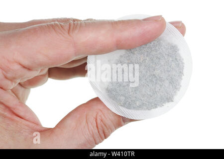 An elderly male cook holds in his hand  round paper bag with green tea. Isolated on white studio macro shot Stock Photo