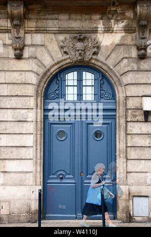 AT BORDEAUX - FRANCE - ON 08/26/2017 - Typical blue door of Bordeaux and a woman walking Stock Photo