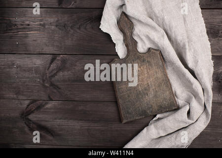 old wooden kitchen chopping boards and a gray towel on a brown table, view from the top Stock Photo
