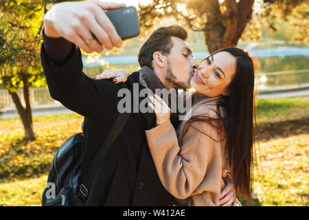 Beautiful loving couple posing walking outdoors in park nature take selfie  by mobile phone. Stock Photo | Adobe Stock