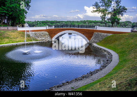 Swan pond with fountain and red footbridge in the city park of Gomel, Belarus Stock Photo