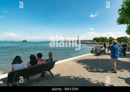 Konstanz, BW / Germany - 14. July 2019: tourists enjoy a beautiful summer day on the shores of Lake Constance with ships passing by Stock Photo