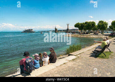 Konstanz, BW / Germany - 14. July 2019: tourists enjoy a beautiful summer day on the shores of Lake Constance with ships passing by Stock Photo