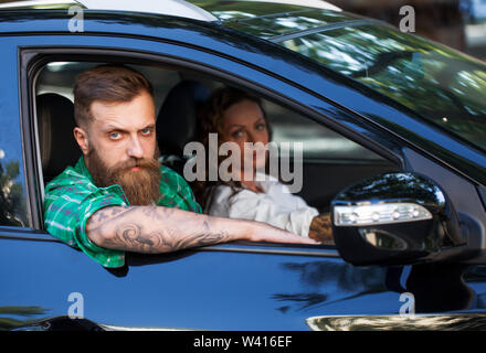 A bearded man with his girlfriend in the car Stock Photo