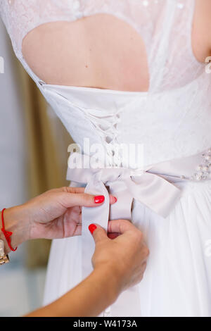Female trying on wedding dress in a shop with women assistant. Stock Photo