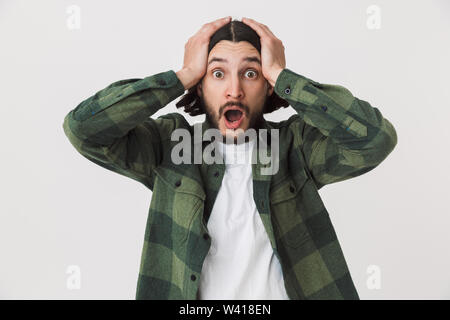Portrait of a confused surprised young bearded brunette man wearing plaid shirt standing isolated over white background Stock Photo