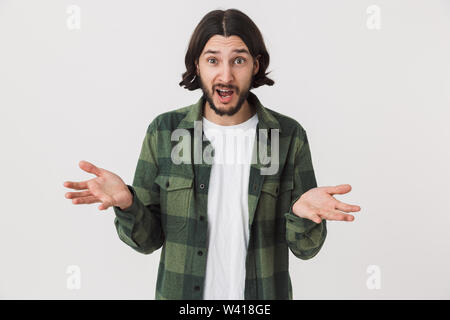 Portrait of a confused surprised young bearded brunette man wearing plaid shirt standing isolated over white background Stock Photo