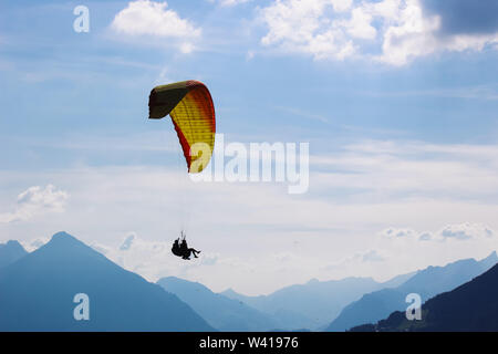 Tandem paragliding in Swiss Alps. Silhouettes of paragliders and beautiful mountains. Extreme sport, adventure sports. Adventurous lifestyle. Concept, conceptual. Stock Photo