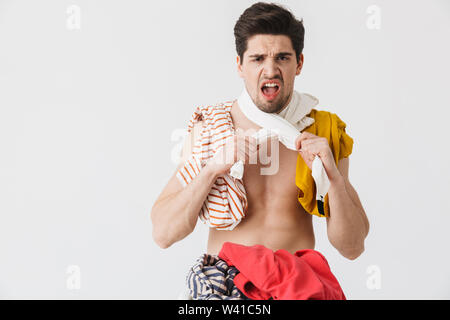 Handsome angry brunette houseman wearing apron standing isolated over white background, choking himself with clothes Stock Photo