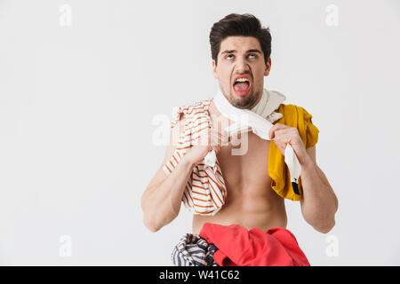 Handsome angry brunette houseman wearing apron standing isolated over white background, choking himself with clothes Stock Photo