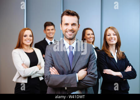 Team leader stands with coworkers in background Stock Photo