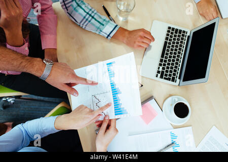 Group of business people discussing graphs sitting at the table. Stock Photo