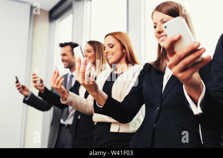 Group of business people standing with smartphones Stock Photo