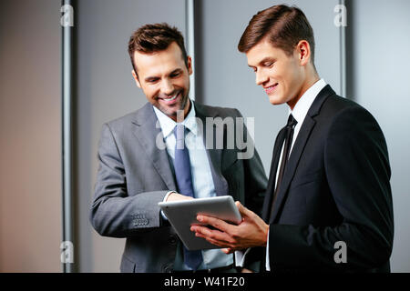 Two young managers talking and looking at a tablet Stock Photo