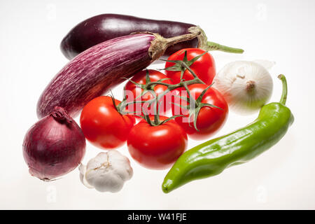 Fresh eggplants, tomatos, green pepper, onion and garlic over white background Stock Photo