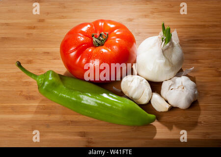 Fresh  tomatos, green pepper, onion and garlic placed in a wooden top Stock Photo