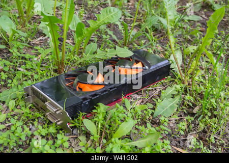 Old and unnecessary computer graphics card thrown to landfill in the grass Stock Photo