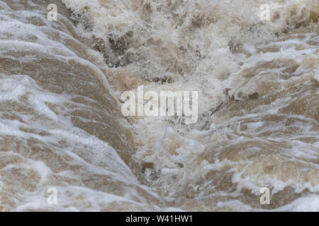 Fast flowing brown water creates waves Stock Photo