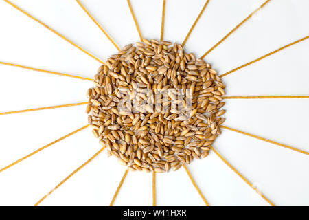 heap of wheat grains and spaghetti in the form of the sun on a white background Stock Photo