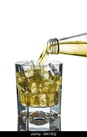 Lemonade is poured into a glass cup from a bottle on a white background, isolate. Stock Photo