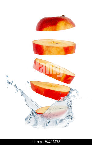 Sliced red apple falls into the water with sprays Stock Photo