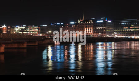 Geneva, Switzerland - November 24, 2016: Night panoramic cityscape with illuminated facades on a riverside in Geneva city. Illuminated Pont de la Mach Stock Photo