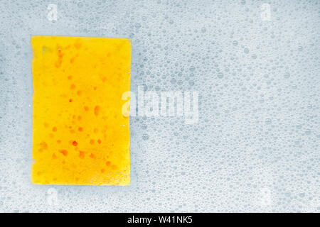 Sponge for washing dishes lies in the foam. Stock Photo