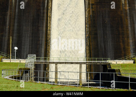 Water flowing over high, steep, concrete dam spillway at Thruscross Reservoir into channel at base (close-up detail) - North Yorkshire, England, UK. Stock Photo