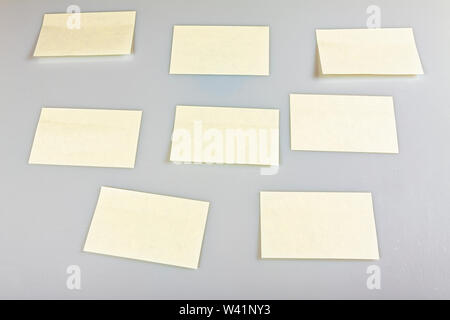 Blank stickers hanging on a white wall, a template for inscriptions. Stock Photo