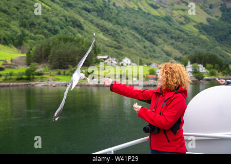 Woman traveling on ferry boat and feeding seagull Stock Photo