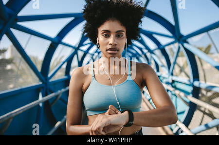 Young fitness woman with smart watch looking at camera. Sportswoman checking pulse on smart watch fitness app. Stock Photo