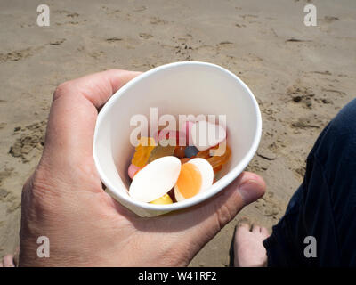 Pick n mix in a cup on the beach Stock Photo