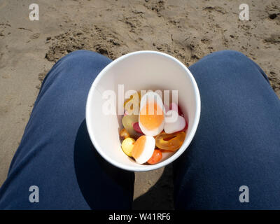 Pick n mix in a cup on the beach Stock Photo