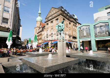 Dortmund, Germany: Blaeserbrunnen (horn blower fountain) on the 'old market place' with the Adler pharmacy and the Protestant church St. Reinoldi in the background.    ---   Dortmund: Blaeserbrunnen auf dem 'Alter Markt' mit der Adler Apotheke und der evangelischen Stadtkirche St. Reinoldi im Hintergrund. Stock Photo