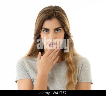 Surprised young woman in her twenties feeling afraid covering mouth in shock reaction, looking with fear in her eyes. People and Human expressions and Stock Photo