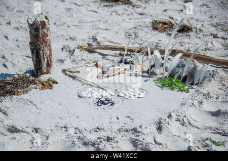 11 July 2019, Mecklenburg-Western Pomerania, Kloster: Holidaymakers have decoratively arranged flotsam on the wide sandy beach between the towns of Mitte and Kloster on the Baltic island of Hiddensee in the sand. Thousands of holidaymakers and day guests are counted daily on the island during the summer months. Hiddensee is largely car-free and horse and cart is a widely used means of transport. Hiddensee is about 16.8 kilometres long, at its narrowest point about 250 metres wide and at its widest about 3.7 kilometres wide. Within the National Park Vorpommersche Boddenlandschaft it is the larg Stock Photo